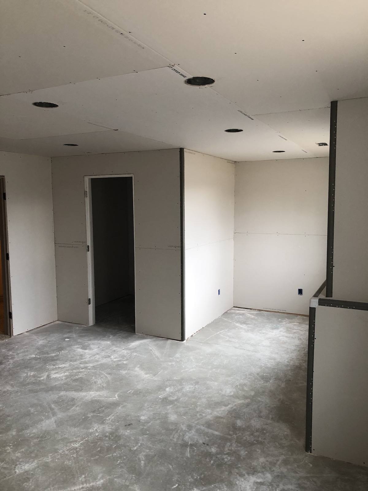 Basement walls and ceiling with drywall hung and ready for taping, concrete floor still exposed