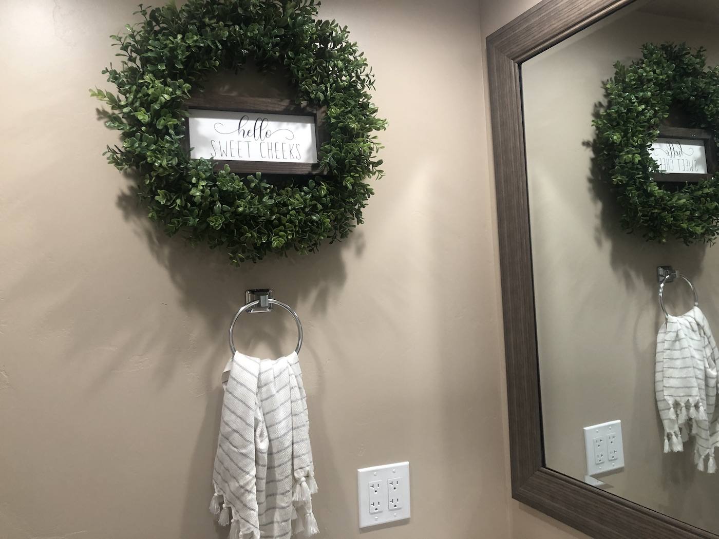 A finished bathroom wall with custom texture, a wreath and mirror hung on it
